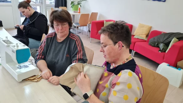 Jede nach ihren M&ouml;glichkeiten: Anleiterin Melanie Haxter hilft Iris Borowski bei der Clutch, die aus echtem Leder gefertigt ist, w&auml;hrend Moniique Neubert im Hintergrund eine Hose gek&uuml;rzt hat. - &copy; Marianne Schwarzer