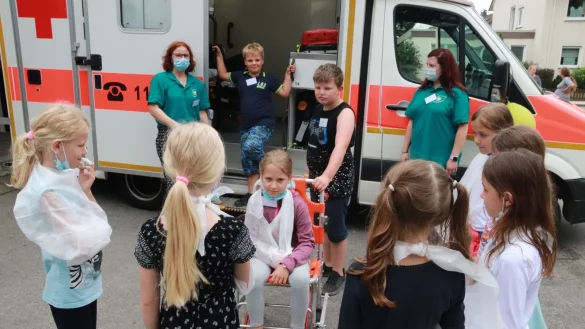 Am Ende des Kennenlerntags beim Deutschen Roten Kreuz wirken die neun Kinder mit den angelegten Dreieckt&uuml;chern wie lauter Verletzte. - &copy; Knut Dinter