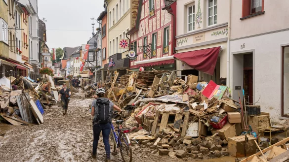 In Ahrweiler in Rheinland-Pfalz schiebt eine Frau ihr Fahrrad durch den Schlamm. Anwohner und Ladeninhaber versuchen, ihre H&auml;user vom Dreck zu befreien und unbrauchbares Mobiliar nach drau&szlig;en zu bringen. - &copy; Thomas Frey/dpa