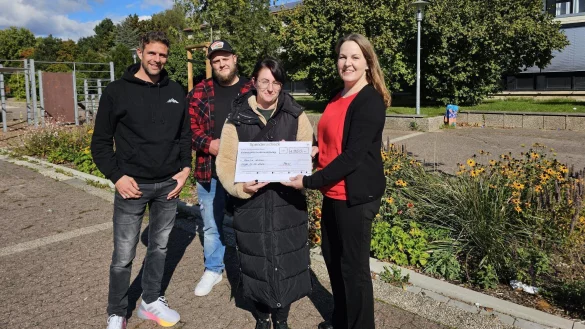 Jens Bielstein, Lehrer am Gymnasium Werreanger, (von links) hat die Spendensammlung f&uuml;r David und Michelle Wilson organisiert. Die Familie hatte bei dem Brand in der Langen Stra&szlig;e alles verloren. Schulleiterin Nadine H&ouml;ner &uuml;berreicht den Scheck &uuml;ber 1350 Euro. - &copy; Astrid Sewing