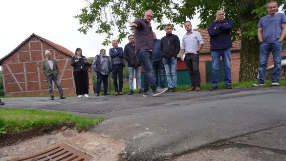 Gregor G&uuml;nnewich, Fachbereichsleiter f&uuml;r Stadtentwicklung, Planen und Bauen, zeigt den Mitgliedern des Ausschusses, wie die so genannte Asphaltwulst das Wasser in den Kanal lenkt. - &copy; Michaela Wei&szlig;e