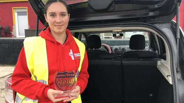 Jana Diser zeigt steht an ihrem Auto, in der Hand hält sie die Auszeichnung als „Heldin der Straße", die sie für ihren Einsatz im vergangenen Juni bekommen hat. - © Sven Kienscherf