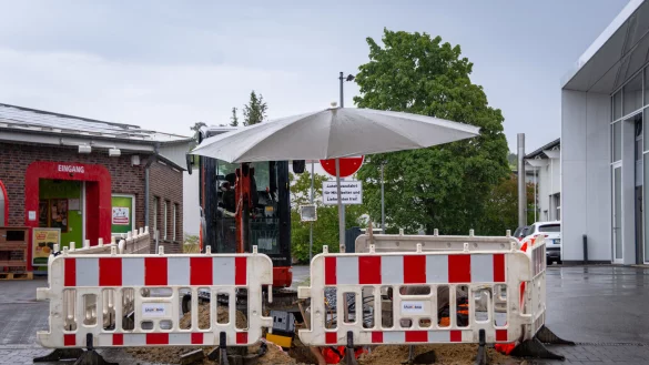 Bauarbeiter reparieren am Dienstag Sch&auml;den an einer Internet-Kupferleitung an der Klingenbergstra&szlig;e. Den wiederkehrenden Regenschauern trotzen sie mit einem Sonnenschirm &uuml;ber der Grabungsstelle. - &copy; Raphael Bartling