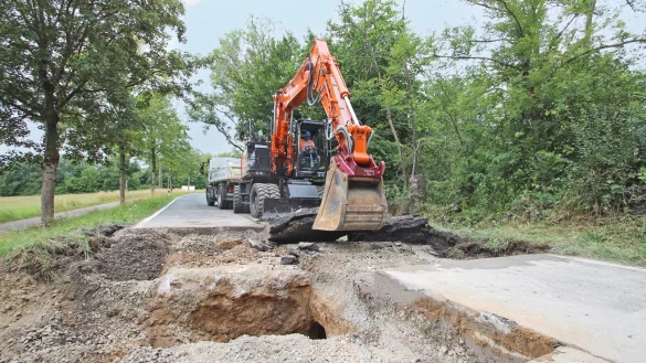 Bauarbeiter haben am Mittwoch angefangen, das Loch unter dem Schwelentruper Weg freizulegen. Dort hat sich ein Hohlraum mit einem Durchmesser von 80 bis 90 Zentimetern gebildet, der sich &uuml;ber die ganze Stra&szlig;enbreite erstreckt. Diesen hat das Wasser des angrenzenden Teichs verursacht. - &copy; Jens Rademacher