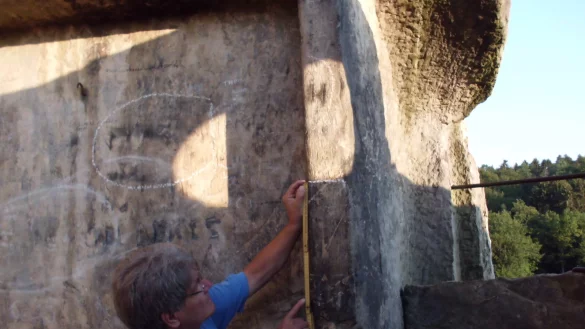 Ralf Koneckis-Bienas dokumentiert den Abstand der waagrechten Lichtschranke der Sonne am 9. August 2022 gegen 6.02 Uhr in der H&ouml;henkammer von Felsen II zum unteren Steingesicht. - &copy; Foto: Dirk M&uuml;ller