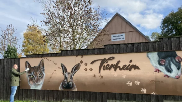 K&uuml;nstler Maik Enge zeigt das Kunstwerk, das er auf dem Zaun des Franziskushofs gestaltet hat. - &copy; Fotorechte: Tierheim Franziskushof