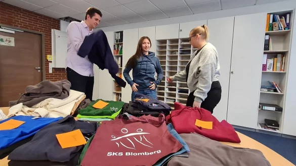 Vertrauenslehrer André Kahle, Schülersprecherin Sabina Galle und Schulleiterin Monika Precker probieren mal die Ansichtsexemplare an. - © Marianne Schwarzer