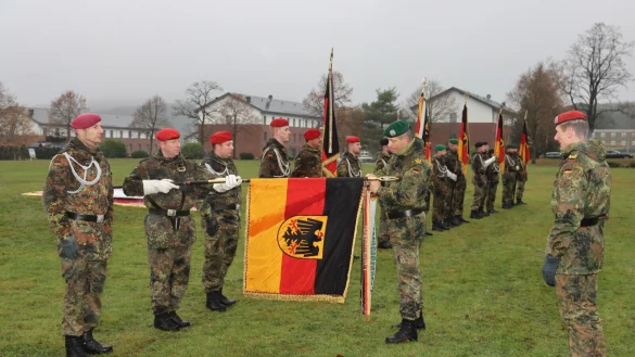 Hohe Auszeichnung: Divisionskommandeur Heico H&uuml;bner (Bildmitte) befestigt das Fahnenband &bdquo;Einsatz&ldquo; an der Truppenfahne des Panzerpionierbataillons 1 aus Holzminden. Brigadekommandeur Stephan Willer (rechts) freut sich &uuml;ber die Ehrung der Bataillone der Panzerbrigade 21. - &copy; Bundeswehr / Nicolai Ulbrich