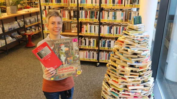 Sarah Zimmert zeigt zwei ihrer Lieblingsb&uuml;cher, neben ihr der Weihnachtsbaum aus B&uuml;chern in der Stadtb&uuml;cherei. - &copy; Alexandra Schaller