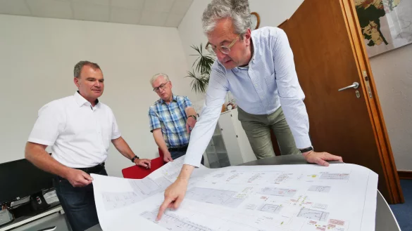 Bauamtsleiter Claus Rafael M&uuml;ther schaut sich mit Josef Sicken und Marcus G&uuml;lle vom Paderborner Ingenieurb&uuml;ro G&uuml;lle Pl&auml;ne zum Eggebad an. Alles, was rot und gelb markiert ist, muss ausgetauscht werden. - &copy; Jost Wolf