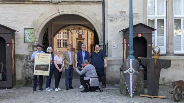Laden zum Jubil&auml;um: Frank Huismann und Elke Treude (beide Falkenburgverein), Schloss-Kuratoin Lisa Marie Bergann, Burgeigent&uuml;mer Stefan Prinz zur Lippe sowie Helmut Merwitz und J&ouml;rn Saak (von links). Knieend ist Vereinsmitglied Klaus Betke zu sehen. - &copy; Falkenburgverein
