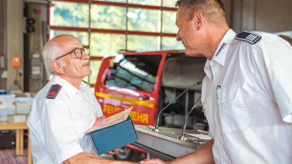 Der kommissarische stellvertretende Leiter der Feuerwehr Bad Salzuflen, Christian Drewes, dankt Reinhold Wiesekopsieker f&uuml;r seine 50-j&auml;hrige Treue zur Feuerwehr. - &copy; FreitagTV