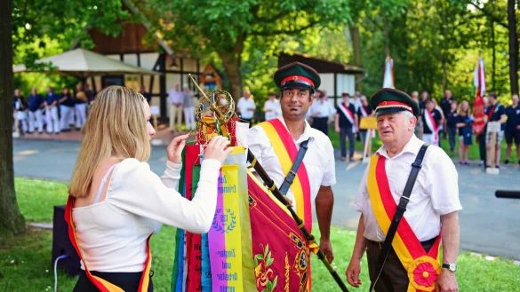 Sven Schnoor (links) und Karl-Heinz Tesching vom Ziegler- und Arbeiterverein Kalldorf nehmen die Jubiläumsfahne in Empfang. - © Nicole Ellerbrake