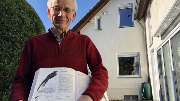 Ulrich Lange zeigt in einem Vogelbuch einen Mauersegler. Im Hintergrund sieht man die Nistk&auml;sten am Fenster links, die au&szlig;erhalb der Nistzeiten abgeklebt werden.&nbsp; - &copy; Sven Kienscherf