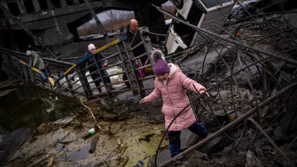Ein Mädchen flieht mit seiner Familie über eine zerstörte Brücke am Rande von Kiew. Foto: Emilio Morenatti/AP/dpa - © (c) AP