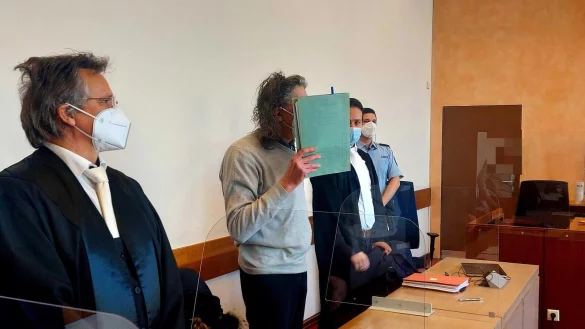 Die Verteidiger Ralph Niemeier (vorne) und Jan-Christian Hochmann stehen an der Seite ihres Mandanten. Der 59 Jahre alte Salzufler ist wegen zweifachen Mordes angeklagt und schützt sein Gesicht mit einer Akte. - © Janet König