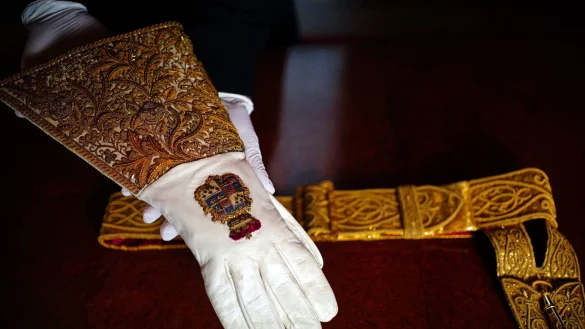 Der Kr&ouml;nungshandschuh und der Schwertg&uuml;rtel, die Teil des Kr&ouml;nungsgewandes sind, sind im Thronsaal des Buckingham Palace zu sehen. Die Gew&auml;nder werden von K&ouml;nig Charles III. bei seiner Kr&ouml;nung am 6. Mai in der Westminster Abbey getragen. - &copy; dpa