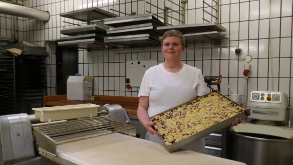 Felix Johann auf der Heide steht mit einem frisch gebackenen Kirsch-Streusel-Kuchen an der Ausrollmaschine bei der Bäckerei Wiebusch in Schötmar. - © Alexandra Schaller