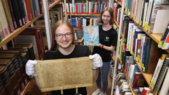 Lukas Tuschewitzki zeigt eine alte Urkunde von 1515 - er ist Auszubildender im Salzufler Stadtarchiv. Mylene Deppermann h&auml;lt ein Bilderbuch - sie macht ihre Ausbildung in der Stadtb&uuml;cherei. Beide sind am Ende Fachangestellte f&uuml;r Medien- und Informationsdienste. - &copy; Alexandra Schaller