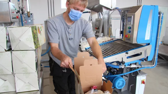 Werner Klemme packt die Beutel mit hei&szlig;em Apfelsaft in Kartons. - &copy; Nadine Uphoff