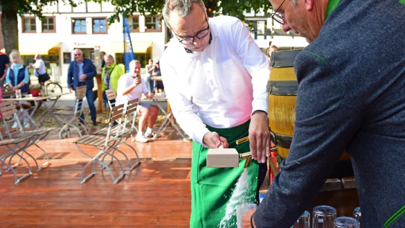 Bürgermeister Markus Baier (links) schlägt das Fass mit Okroberfest-Bier an. Rechts Peter Daldrup von der Paulaner-Brauerei. - © Nicole Ellerbrake