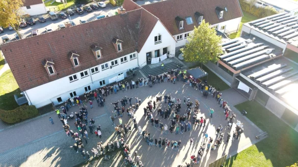 Mit einer Menschenkette umrahmen die Gegner der Schulschlie&szlig;ung in Alverdissen das Geb&auml;ude. Aus der Luft macht eine Drohne Aufnahmen. - &copy; Sylvia Frevert