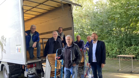 Mehrere hundert St&uuml;hle und Tische finden eine neue Bestimmung: Bernd Hendig, Schulleiter der Karla-Raveh-Gesamtschule (rechts) freut sich mit Friedhold Stock, J&uuml;rgen Wattenberg, Hubertus Sprick, Herbert B&uuml;sching, Georg Nork und Horst J&uuml;ngling (von links), dass die M&ouml;bel in Litauen wieder zum Einsatz kommen. - &copy; Kreis Lippe