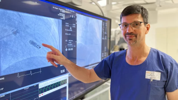 Dr. B&eacute;la B&oacute;zsik zeigt mit seinem Finger auf die kleine Kardiokapsel, dem kleinsten Herzschrittmacher der Welt. - &copy; KHWE