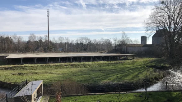 Das betreffende Grundst&uuml;ck an der Ladestra&szlig;e von der Uferstra&szlig;e aus gesehen. Das Motiv zeigt, wie nah sich die 2019 abgebrannte Doppelhalle an der Bega befand. Von dem gro&szlig;en Geb&auml;ude steht nur noch die Betonplatte, die es vor Hochwasser sch&uuml;tzen sollte. Das Grundst&uuml;ck will die Stadt jetzt renaturieren. - &copy; Thomas Reineke