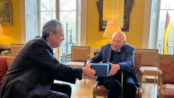 Vernon Katz (rechts) und der deutsche Botschafter Miguel Berger bei der Wiedereinb&uuml;rgerung von Vernon Katz 2022 in der deutschen Botschaft in London. Das blaue Paket enthielt ein Pr&auml;sent der Stadt Bad Salzuflen (Salz und ein Bild von Sch&ouml;tmar) sowie einen pers&ouml;nlichen Brief des B&uuml;rgermeisters. - &copy; Deutsche Botschaft London