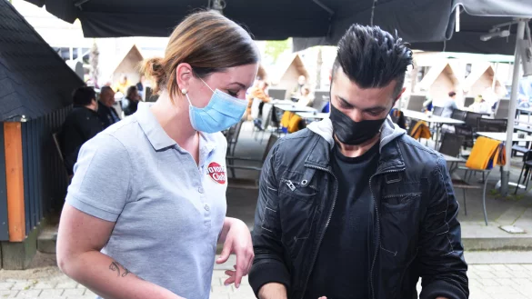 &bdquo;Cosmo Lounge"-Kellnerin Stephanie Wolf zeigt ihrem Gast Orkan Korkmaz, wie er mit der Anwendung &bdquo;Darf ich rein?" seine Daten f&uuml;r die Kontaktnachverfolgung speichern kann. Erst danach gibts die Speisekarte.&nbsp; - &copy; Raphael Bartling