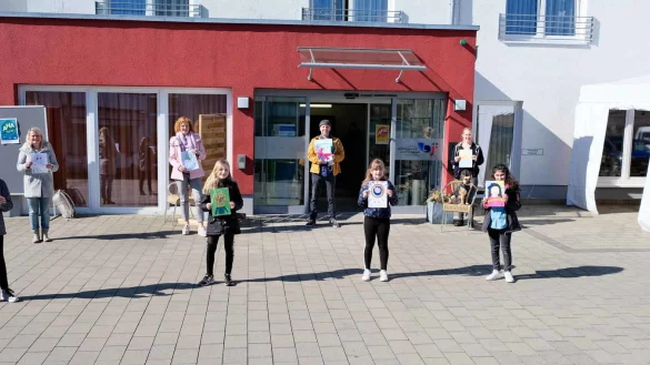 Kinder der Grundschule am Schloss (von rechts, Tobias, Finja, Lotta, Charlotte und Lya) &uuml;berreichen zusammen mit Lehrerin Alexandra Kehl (von links), Saskia Frei-Klages vom Kreis Lippe und K&uuml;nstler Stefan Sch&auml;fer ihre Bilder an Nora Meierhenrich vom Ev. Altenzentrum am Schloss. - &copy; Kreis Lippe