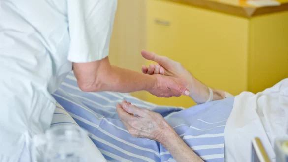 Eine Krankenpflegerin der Onkologie h&auml;lt die Hand eines Patienten. &bdquo;Das ist ein Beruf, in dem man sehr viel zur&uuml;ckbekommt &ndash; von den Pflegebed&uuml;rftigen und auch von den Angeh&ouml;rigen", sagt Annette Heuwinkel-Otter. - &copy; dpa / Daniel Karmann