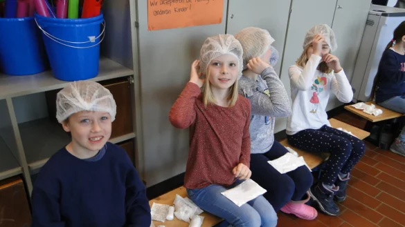 Sebastian, Melina, Emma und Emilie öffnen das Erste-Hilfe-Paket, dass Trainerin Alexandra Lühmsmeyer mit in die Schule gebracht hat (von links). Erste Handlung: Haarnetz anlegen. - © Hajo Gärtner