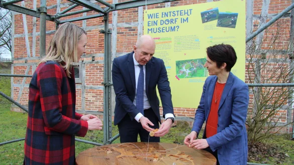 Ausstellungskuratorin Anna Stein, LWL-Direktor Dr. Georg Lunemann und Museumsdirektorin Dr. Marie Luisa Allemeyer (von links) an einer der neuen Stationen. Anhand des Holzpuzzles soll begreifbar werden, wie ein Dorf im Museum entsteht. - © Jana Beckmann