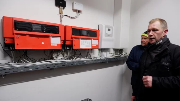 Andreas Ens, Mitglied der Energiekommission und Heizungsmonteur, erklärt die neue Anlage in der Feuerwache Silixen. - © Lorraine Brinkmann