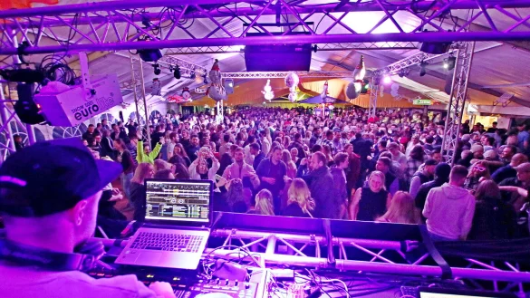 DJ Marcel Welgen hat von seinen Mischpulten aus das in buntes Disko-Licht eingeh&uuml;llte und proppevolle Festzelt bestens im Blick. Unter der Decke h&auml;ngen passend Deko-Schlitten und Schneem&auml;nner. - &copy; Patrick Bockwinkel