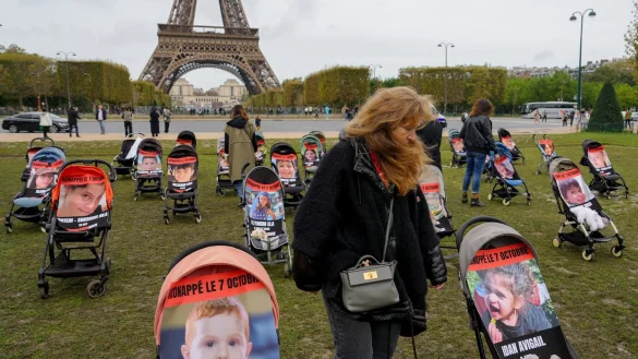 Eine Frau geht neben den Kinderwagen mit Bildern der jungen Geiseln Bibas Ariel (l.) und Idan Avigail (r.), die unter anderem als Symbol f&uuml;r junge Geiseln gezeigt werden. - &copy; AFP or licensors