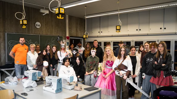 Gruppenbild mit Barbie: Von links: Dennis Reimer (Rapschool NRW) , Eva Ruthe (Dozentin), Karin Hoppe Boske (Lehrerin Realschule Lemgo), achte von links: Dorothee Meier (Schulleitung Realschule Lemgo), Daniel Schneider (Leitung Rapschool NRW), zehnter von rechts: Thomas Mahlmann (zdi-Zentrum Lippe.MINT) mit den jungen Cosplayerinnen und Cosplayern. - &copy; Lippe Bildung eG