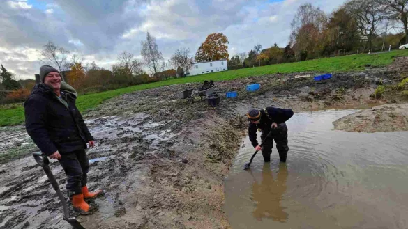 Andreas Beerens (links) und Andreas Gossen setzen Wasserpflanzen in den frisch ausgebaggerten Teich an der Stra&szlig;e Asperheide. Sp&auml;ter sollen hier Amphibien laichen. - &copy; Ulrich Kaminsky