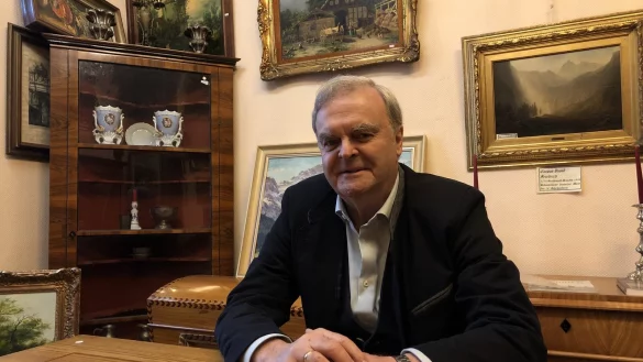 Michael Rosteck sitzt an einem alten Holztisch in einem der Verkaufsr&auml;ume. Rechts hinter ihm h&auml;ngt ein Motiv von Caspar David Friedrich. Das sei aber unverk&auml;uflich, betont der Lemgoer. - &copy; Sven Kienscherf