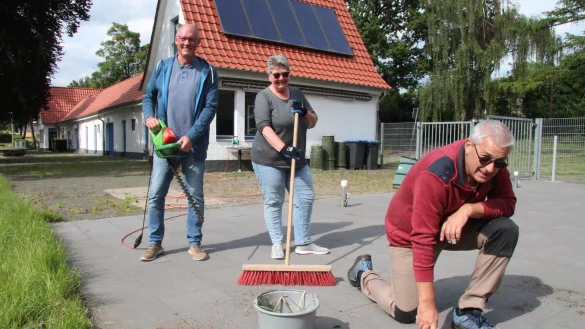 Eine l&auml;stige, aber notwendige Arbeit: Thomas Schneider (vorn), Bernhard Bentler und Angelika Schneider kratzen beim Arbeitseinsatz im Eggebad Unkraut aus den Fugen, stutzen Str&auml;ucher und halten den Kioskbereich in Schuss. - &copy; Dieter Asbrock