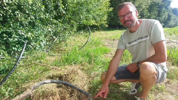 Kleinenmarpes Ortsvorsteher Frank Wilde zeigt das Telekom-Kabel, das erneut durch M&auml;harbeiten besch&auml;digt wurde. Er hofft, dass das Kabel, das derzeit frei im Stra&szlig;engraben und auf der angrenzenden Wiese liegt, zeitnah erdverlegt wird. - &copy; Michaela Wei&szlig;e