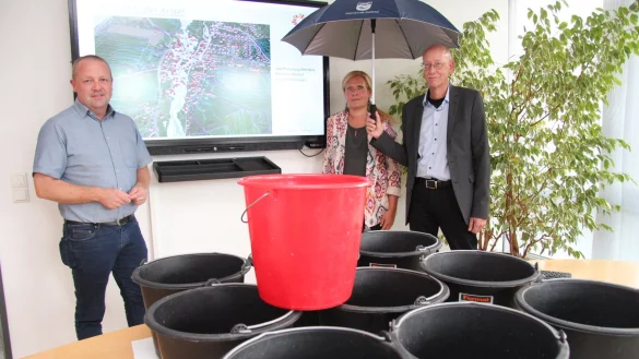 B&uuml;rgermeister Mario Hecker (von links), Gemeindemitarbeiterin Corinna Will und R&uuml;diger Kuhlemann vom Kreis Lippe beim Vortrag zum Thema "Wasser in der Krise". Die Eimer sollen verdeutlichen, wie viel Regen auf einen Quadratmeter bei einem Starkregenereignis innerhalb k&uuml;rzester Zeit fallen kann. - &copy; Nadine Uphoff
