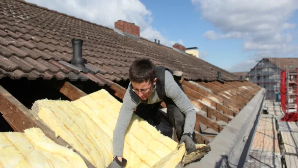 Dachdeckerin Anja van Ißem dämmt das Dach eines Hauses mit Mineralwolle – nur ein Baustein, um aus einer Energieschleuder ein Effizienzhaus zu machen. - © picture alliance / dpa