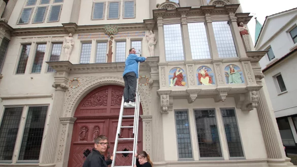 Museumsleiter Fabian Schröder misst die Eva-Figur an der Front des Hexenbürgermeisterhauses, Hausmeister Stephan Schäfsmeier und Museumsaufsicht Maike Reichert halten die Leiter. Fragen wie die nach der Figurengröße werden beim "Kultur-Quiz" am Freitag, 4. Oktober, gestellt. - © Jens Rademacher