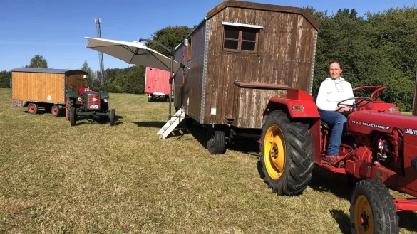 Nicole M&uuml;gge sitzt auf dem Trecker, der einen alten Bauwagen zieht. Um die 200 Fahrzeuge werden beim Treffen in W&uuml;sten zu sehen sein. - &copy; Sven Kienscherf