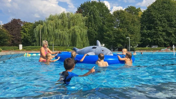 Sabine Pettig bringt ihren Seepferdchen-Schülern spielerisch das Schwimmen bei - hier mit einem großen aufblasbaren Hai. - © Carolin Brokmann-Förster