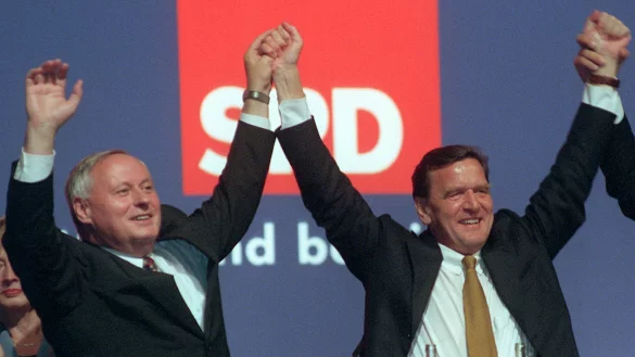 Der damalige SPD-Kanzlerkandidat Gerhard Schr&ouml;der (r.) und der damalige Parteivorsitzende der Sozialdemokraten, Oskar Lafontaine, halten sich am Abend bei der Wahlkampfabschlussveranstaltung ihrer Partei in Berlin an den H&auml;nden. - &copy; Peer Grimm