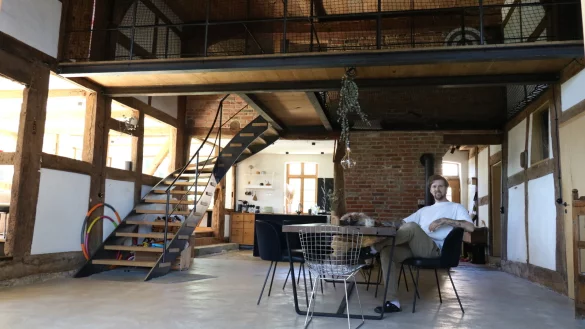 Nick Pyka sitzt in der gro&szlig;en Deele, hinter ihm f&auml;llt der Blick in die offene K&uuml;che. Den Zwischenboden hat er selbst eingezogen. - &copy; Alexandra Schaller